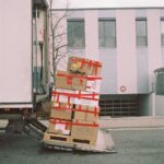 Brown cardboard boxes stacked on a pallet near the back of a truck