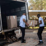 Two men moving boxes into a truck