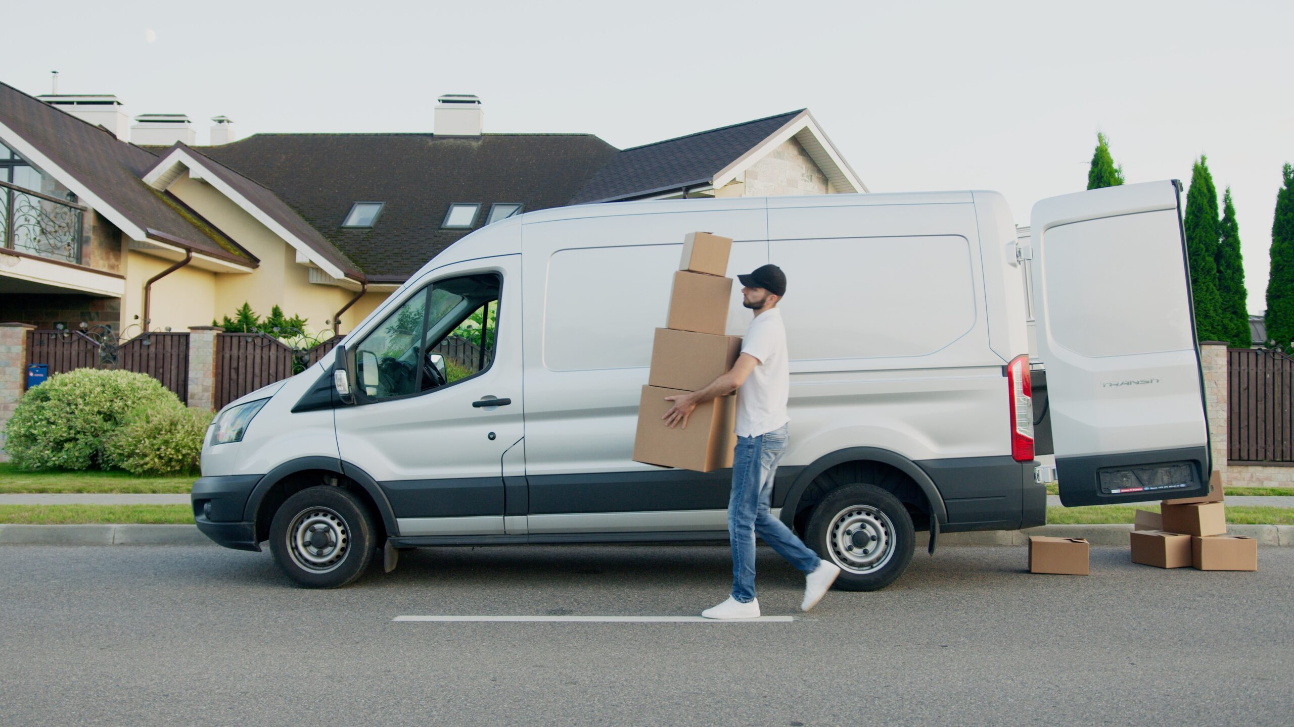 Man in a black cap loading boxes into a van
