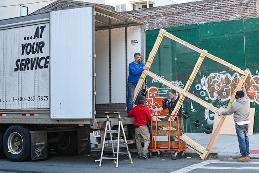 People loading a wooden frame into a moving truck.
