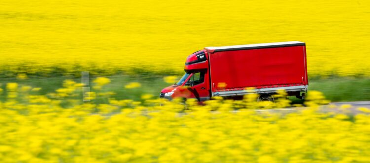 Red truck driving past yellow fields