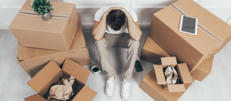 A man looks stressed out while packing moving boxes.